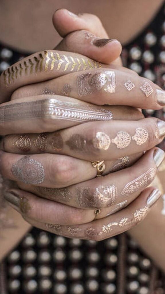 hands interlaced with gold temporary henna tattoos