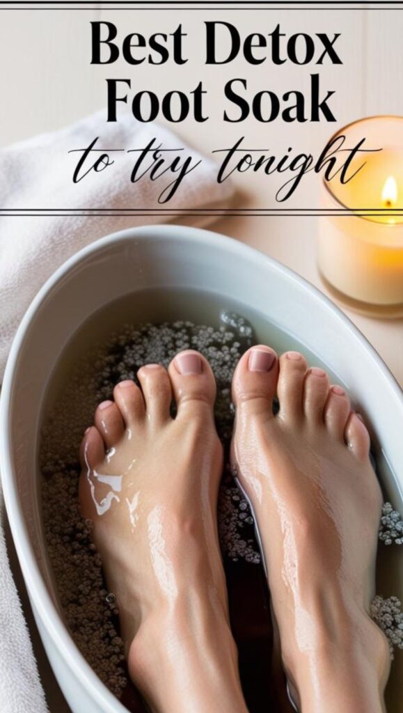 Close-up of feet soaking in a white bowl filled with a homemade foot soak of Epsom salt, vinegar, and warm water, surrounded by a relaxing spa setting with a lit candle. There is overlay text that reads "Best Detox Foot Soak to Try Tonight".